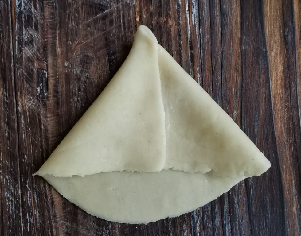 Fold de spidse ender indover, så de samles og danner en kegleform. Brug 50/50 vand og mel som 'klister' til at lukke den tæt. - Hjemmelavet samosa