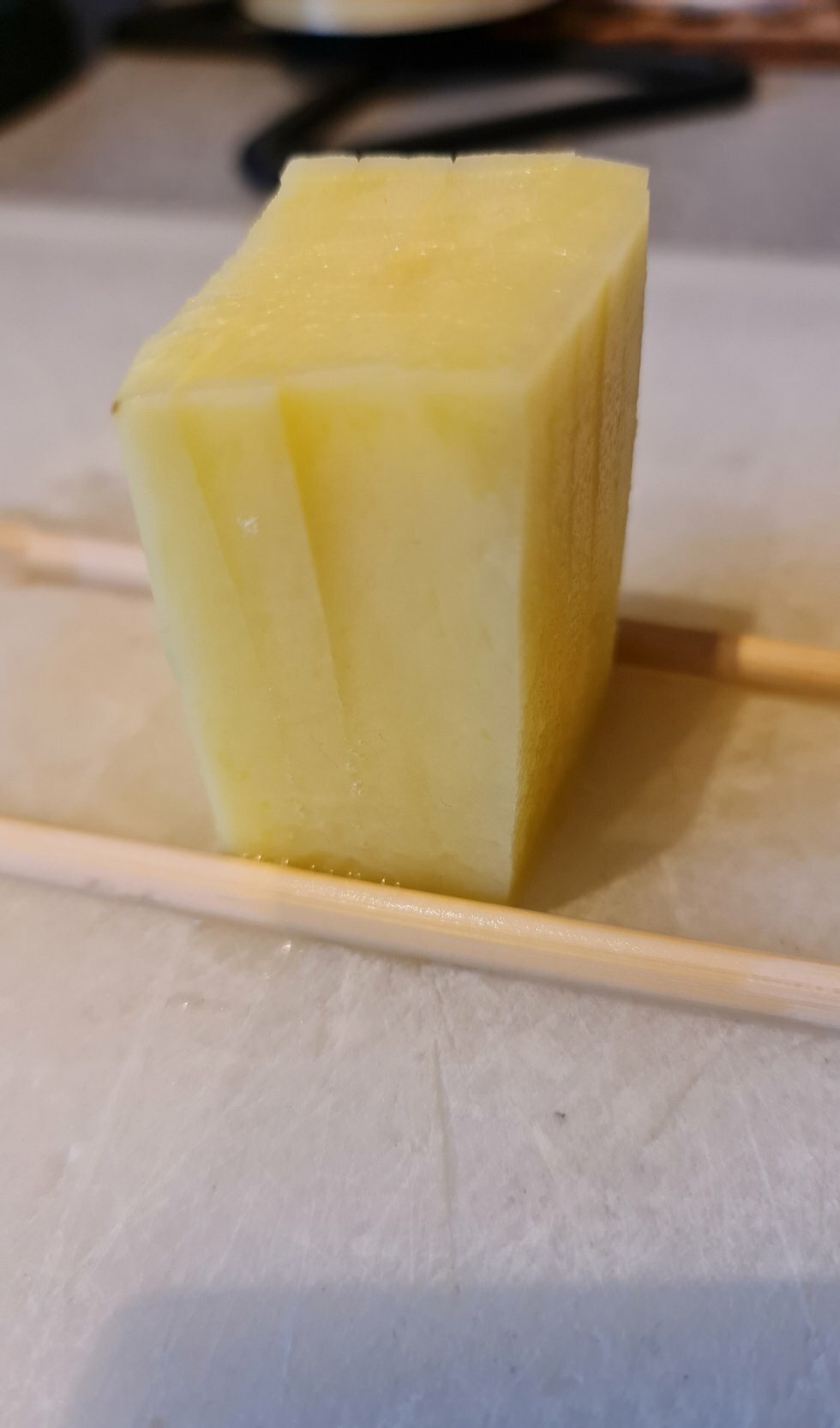 Kartoflen lægges mellem to spisepinde, som sørger for, man ikke skærer helt i gennem. - Pommes frites-palmer